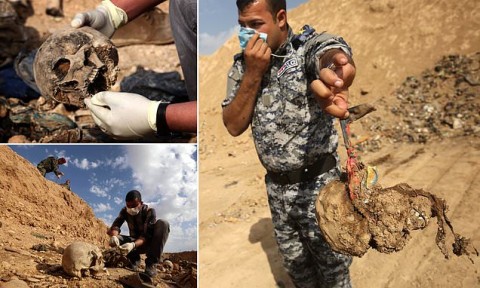A member of Iraq's security forces holds out a skull as he and his comrade cover their noses from the stench at a mass grave uncovered in the Hamam al-Alil area in November 2016. Photo: AFP / Getty Images