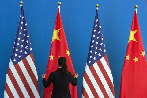 A Chinese woman adjusts a Chinese flag near US flags before the start talks between the two nations in 2014. Photo: Ng Han Guan/AFP/Getty Images