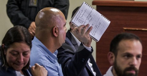 Durante las primeras audiencias, el alcalde Cardona intentó ocultarse de las cámaras usando su libreta. 