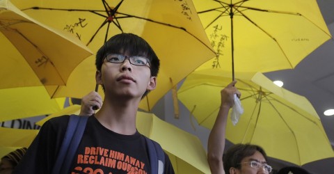 Joshua Wong stands in front of yellow umbrellas, the symbol of the 2014 Hong Kong protests, ahead of a 2015 court hearing. Photo: Vincent Yu / AP