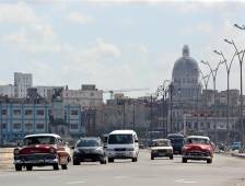 Several cars passing by the pier in Havana