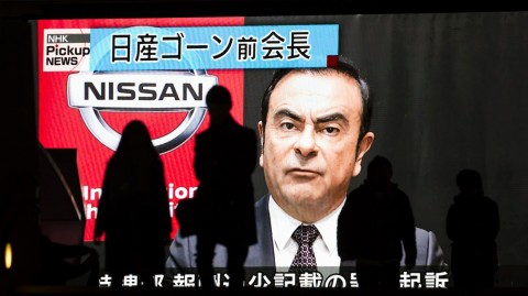 Pedestrians walk in front of a monitor showing an image of former Nissan Motor Co. Chairman Carlos Ghosn on Monday in Tokyo, Japan. Photo: Tomohiro Ohsumi/Getty Images