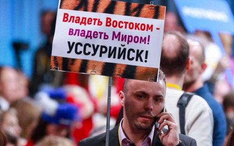 Journalists carry signs made to grab the Russian leader's attention. Photo: Sergei Fadeichev / TASS via Getty Images 