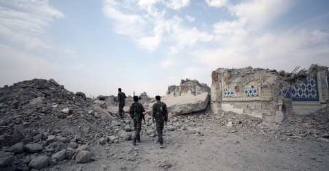 Fighters from the Syrian Democratic Forces stand near the destroyed Uwais al-Qarni shrine in Raqqa, Syria. Photo: Rodi Said / Reuters