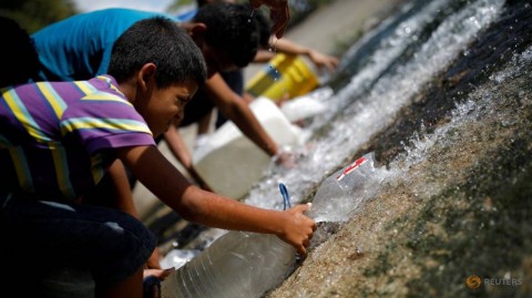 People collect water released through a sewage drain that feeds into the Guaire River, which carries most of the city's wastewater, in Caracas, Venezuela March 11, 2019.