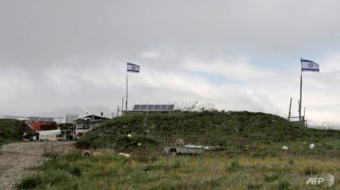 Israeli flags fly over a military base near the border fence with Syria in the Israeli-annexed Golan Heights, south of the Druze village of Majdal Shams.