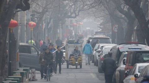 People are seen in a traditional alleyway on a polluted day in central Beijing, China