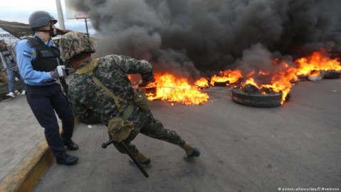 Police and soldiers back away from burning tires lit by protesters (Photo: Delmer Menbrano/dpa)