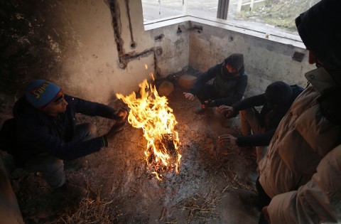 Migrants get warm by a campfire in an abandoned factory in the western Serbian town of Sid, near Serbia's border with European Union member Croatia, Monday, Dec. 18, 2017. Photo: Darko Vojinovic