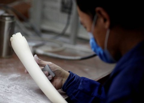 A worker polishes a tusk in an ivory workshop in Beijing last March. | Reuters