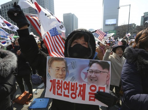 In this March 1, 2018, photo, a conservative activist with a card showing a portrait of South Korean President Moon Jae-in and North Korean leader Kim Jong Un, right, attends a ceremony to celebrate the March First Independence Movement Day, the anniversary of the 1919 uprising against Japanese colonial rule, in Seoul, South Korea. (Photo: Ahn Young-joon/AP)