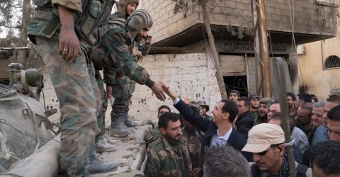 Syrian President Bashar al-Assad reaches out to shake the hand of a Syrian army soldier in eastern Ghouta, Syria, March 18, 2018. Sana / Reuters
