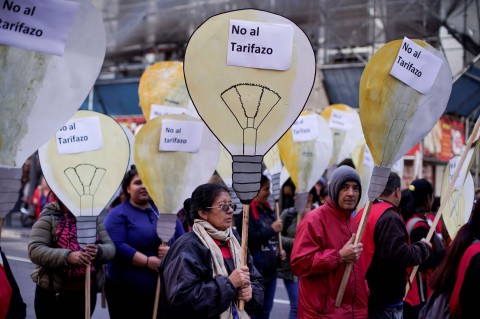 People hold cutouts that look like light bulbs with signs that read in Spanish 