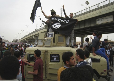 In this Sunday, March 30, 2014, file photo, Islamic State group militants hold up their flag as they patrol in a commandeered Iraqi military vehicle in Fallujah, 40 miles (65 km) west of Baghdad. (AP Photo, File)