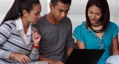A group of students check a laptop computer. Photo: Shutterstock.com