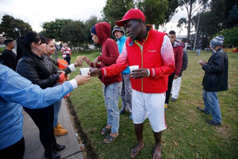 People in Bogota, Colombia, hand food to Venezuelan migrants camping in a park near the main bus terminal. Photo: AP